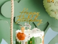 tort urodzinowy w stylu safari ze złotym toperem Happy Birthday i świeczkami w kształcie lwa, zebry i słonia